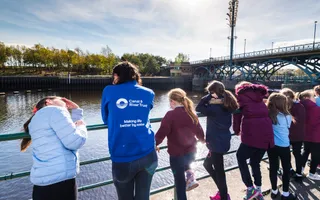 Line of school children stand with Explorers volunteer looking out at River Tees