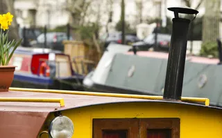 Boats moored on the canal with daffodils in a planter on the roof