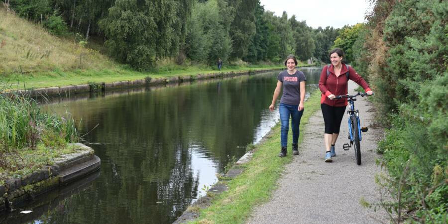 A walker and a dismounted cyclist walking beside a canal in Birmingham