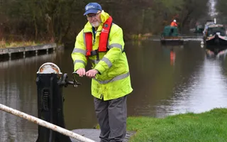 Man in high vis jacket wearing lifejacket and cap using a lock gate