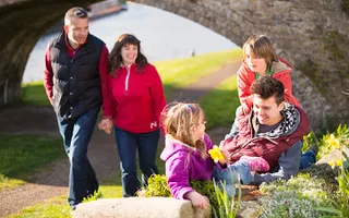 Family walking along the towpath together while the children stop to play