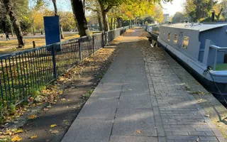 Boats moored along the towpath in Victoria Park, surrounded by autumn leaves