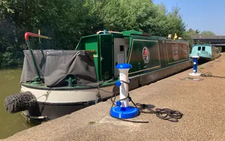 Wide shot of a green canal boat moored up on a canal