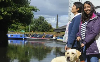 wo people smiling with a dog on the canal towpath
