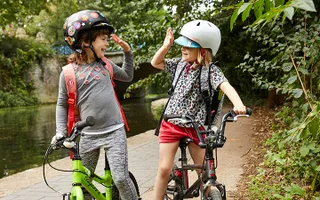 Two children high-five as they cycle on the towpath