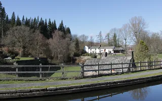 Canal goes round a corner, passing trees and houses