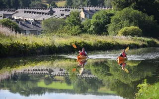 Two people paddle canoes on the canal