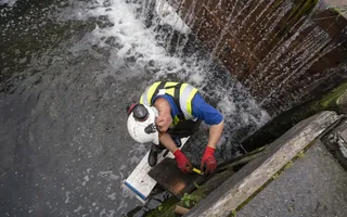 Man stands on platform in empty lock chamber repairing the wall