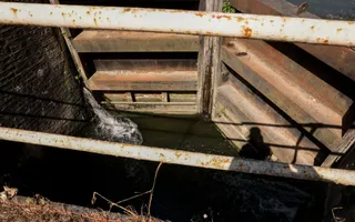 Looking down from the bridge onto the wooden lock gate which has water spurting out the side.