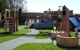 Children playing happily on wooden bridge and playground equipment