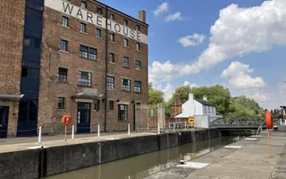 Wide shot of a canal with warehouse and small white house in the background