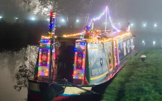 Narrowboat at night time with festive lights around it.