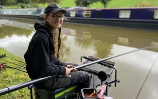 A young person sat on the canal bank fishing