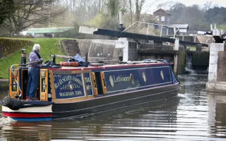 A blue narrowboat enters a double lock on a foggy day.