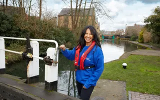 Woman standing next to lock gates and smiling to camera