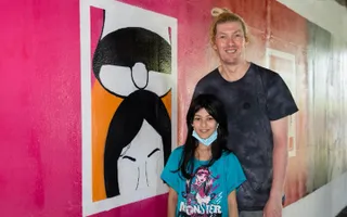 Two people standing next to street art murals on the canal