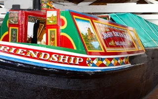 The exterior cabin of a traditional working narrowboat, decorated with roses and castles and its name 'Friendship'