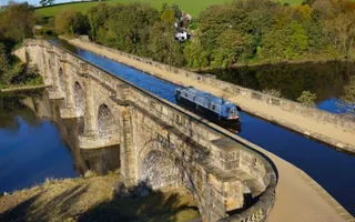 A boat crosses over a multi-arch canal aqueduct