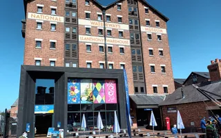 Picnic tables in front of the National Waterways Museum with blue sky behind