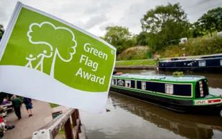 Green Flag Award flag with canal and boat in background