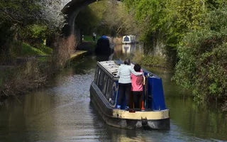 Boat travelling on the canal, surrounded by greenery on a tranquil day