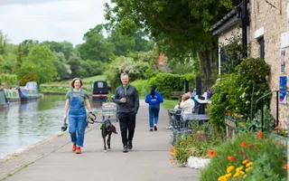 Couple walking dog along canal towpath