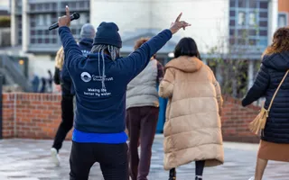 Woman facing away from camera, hands held up and holding microphone
