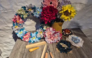 Floral wreath on table with craft tools and colourful material in the shape of flowers
