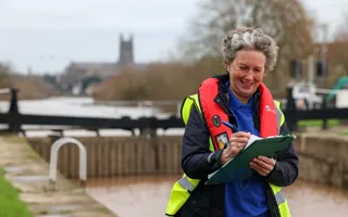 Volunteer making notes on clipboard, by the canal