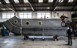 Half of a metal sculpture of a narrowboat inside a warehouse