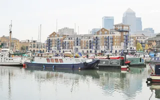 Boats moored in basin with London Docklands in background