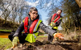 Two Canal & River Trust volunteers plant greenery on the canal towpath