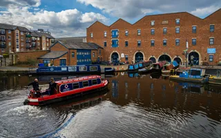 Boats moored in a marina in front of a large industrial-era warehouse.
