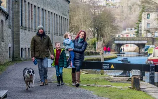 Family walking along the towpath with a dog on the left