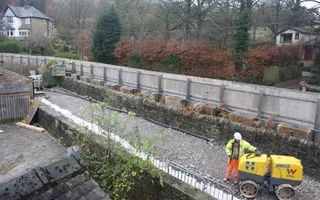 Worker with a roller standing on gravel