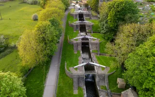 Aerial view of five empty staircase locks, surrounded by verdant greenery, grass, and trees.