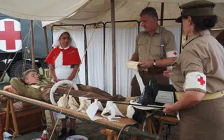 People in 1940s military uniform standing around patient