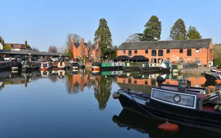 Canal boats moored across a basin, surrounded by converted red-brick warehouses