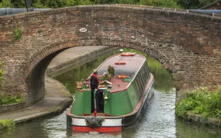 Narrowboat travelling under an arch bridge