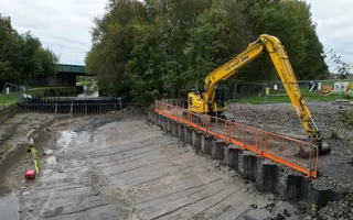 Wide shot of a drained canal with digger on the right.