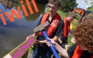 Volunteers hammer a fence together along the canal towpath