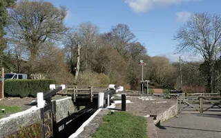 Lock with open gates surrounded by trees next to a road
