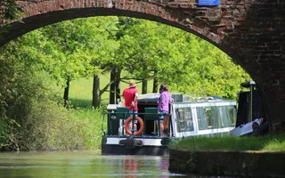 A boat cruising under a bridge