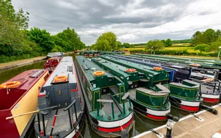 Green narrowboats moored in canal basin
