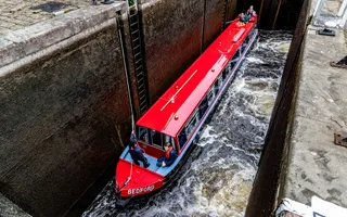 A red narrowboat descends into a steep lock