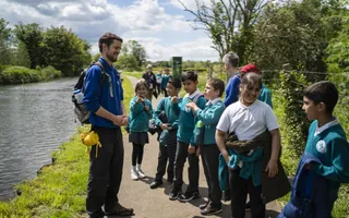 Group of schoolchildren in uniform on a towpath with staff member and teachers