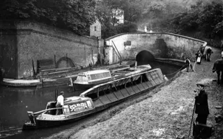 Old black and white photo of a canal tunnel with canal work boat