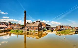 Water in the foreground, old brick building with tall chimney