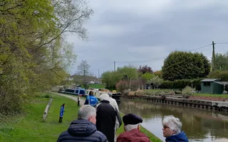 Group of people walking along a towpath on a cloudy day