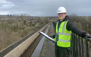 Worker in yellow vest and hard hat stands on canal aqueduct